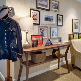 A cozy interior with a wooden console table, decorated with framed photos and a lamp, alongside a coat on a stand.