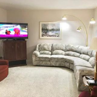 A cozy living room setting with a sectional sofa, television, and decorative wall elements.