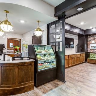 A modern cafe interior featuring a display case, wooden furnishings, and stylish lighting.