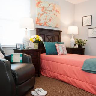 A cozy bedroom with a coral bedspread and matching decor.