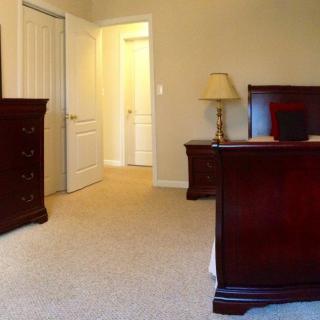 A cozy bedroom with wooden furniture and soft carpet flooring.