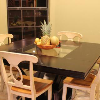 A dining area featuring a modern table with a fruit bowl centerpiece and chairs.