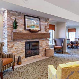 A cozy living room featuring a stone fireplace, comfortable armchairs, and warm decor.