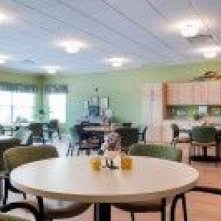 A cozy dining area with tables, chairs, and a kitchenette in the background.