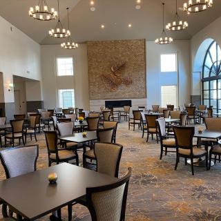 A spacious dining hall with elegant chandeliers and neatly arranged tables and chairs.