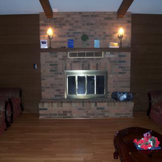 A cozy living room with a central brick fireplace and wooden flooring.