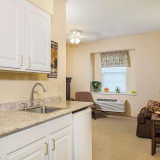 A cozy kitchen area leading into a comfortable living room with light-colored walls and modern furnishings.