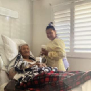 A patient is receiving care from a caregiver in a hospital room.