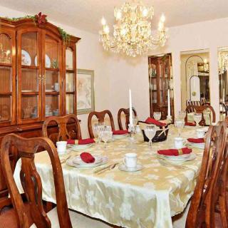 An elegantly decorated dining room featuring a large table with ornate chairs, a sparkling chandelier, and a china cabinet filled with dishes.
