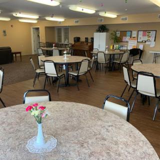 A spacious community room featuring tables and chairs, ideal for gatherings and activities.