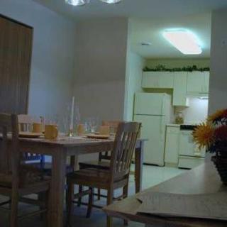 A cozy dining area with a table set for a meal and an adjacent kitchen in the background.