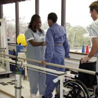 A patient receives assistance from medical staff during a physical therapy session.