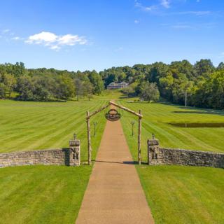 A scenic pathway leads through lush green fields under a clear blue sky.
