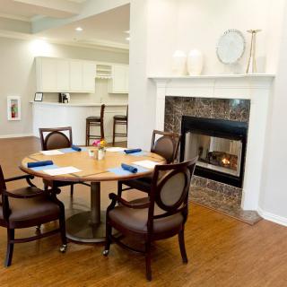 A cozy dining area featuring a round table with chairs and a fireplace.