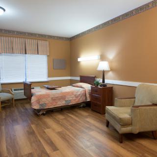A cozy hospital patient room with warm colors and essential furnishings.