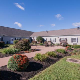 A well-maintained house with landscaped gardens and a paved walkway under a bright blue sky.