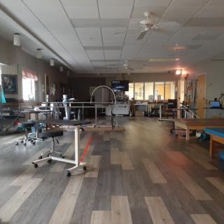 A spacious therapy room in a hospital, equipped with medical equipment and designed for rehabilitation.