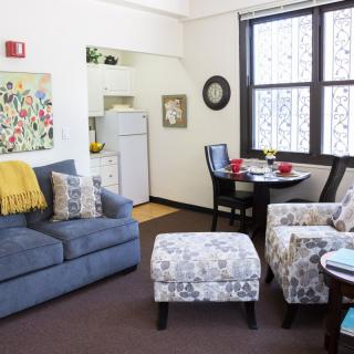 Cozy living space with a sofa, armchair, and dining area adjoining an open kitchen.