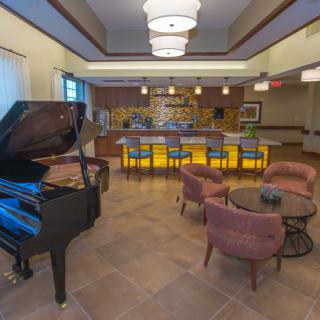 A cozy lounge area featuring a grand piano and a stylish bar with seating.