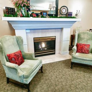 A cozy living room setting with a fireplace and two armchairs adorned with red cushions.