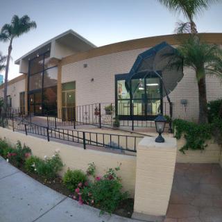 A modern residential building featuring a landscaped front yard and palm trees.