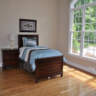 A minimalist bedroom with a single bed and large window allowing natural light.