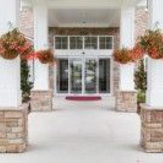 A symmetrical building entrance with columns and hanging potted plants.
