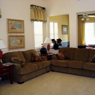 A cozy living room with a brown sectional sofa, decorative lamps, and framed artwork on the walls.