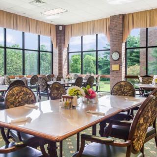 A well-lit dining room with large windows, featuring elegant tables and chairs.