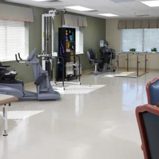 A modern physical therapy and rehabilitation room equipped with exercise machines and therapy tables.