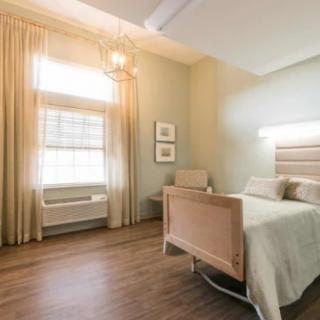A clean and minimalist hospital room with a single bed and window.