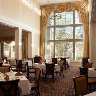 A spacious restaurant dining room with elegant decor and large windows.