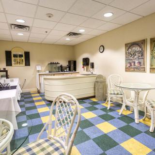 A cozy dining area with checkered flooring, featuring tables and chairs near a coffee station.