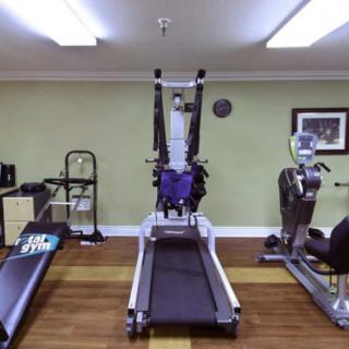 A well-equipped gym with various exercise machines, including a central treadmill.