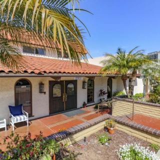 A beautiful house with a tiled roof and a lush garden under a clear blue sky.