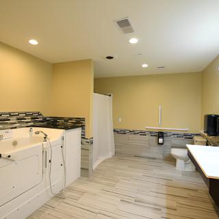 A spacious modern bathroom featuring a bathtub, shower, and toilet with tiled flooring.