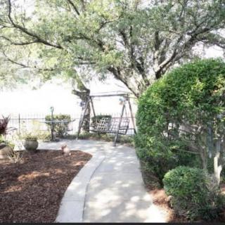 A serene garden pathway surrounded by trees and shrubs, leading to a swing set.