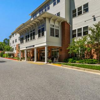 A multi-story residential building with a well-maintained exterior and surrounding greenery on a sunny day.