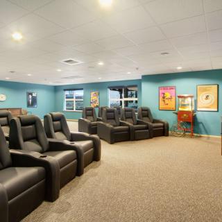 A cozy home theater room with comfortable recliner seating and movie-themed decor.