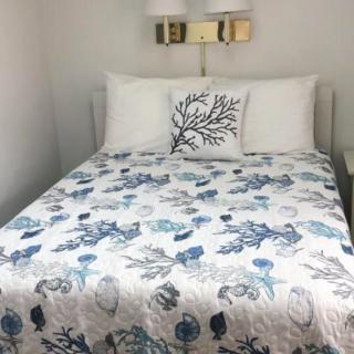 A neatly made bed with floral-patterned quilt and decorative pillows in a well-lit bedroom.