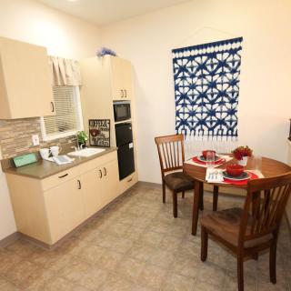 A cozy kitchen with a small dining area featuring wooden chairs, a round table set for two, and modern appliances.