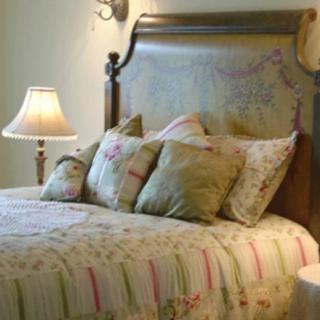 A cozy bedroom with a neatly made bed, decorative pillows, and a warm lamp on the nightstand.