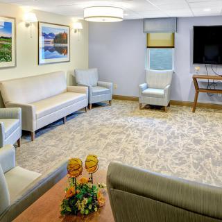 A comfortable waiting room with sofas, chairs, a television, and wall art.
