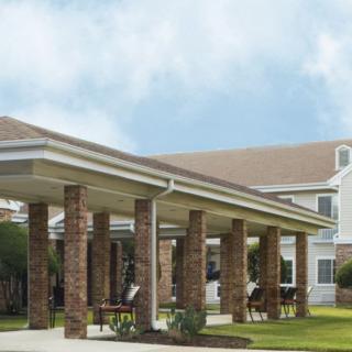 A large building with a covered porch supported by brick columns.