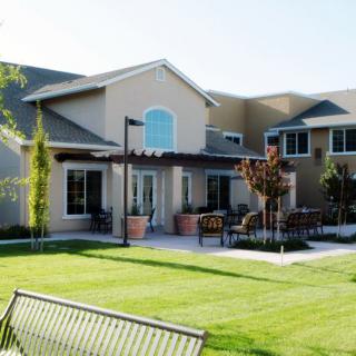 A modern residential building with a well-maintained lawn and outdoor seating area.