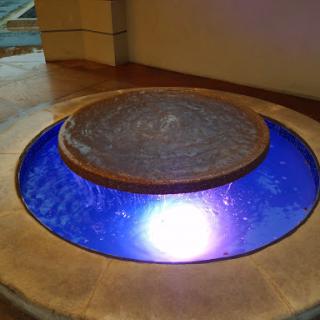 An artistic indoor fountain with vibrant blue lighting, creating a serene atmosphere.