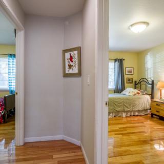 A cozy hallway leading to a warmly decorated bedroom with wooden flooring.