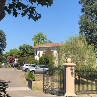 A peaceful residential area featuring a welcoming house and well-maintained garden under a clear blue sky.