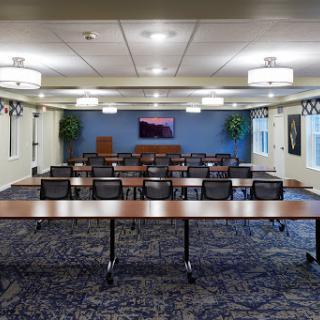 A spacious conference room set up for meetings, featuring tables and chairs arranged for group discussions.