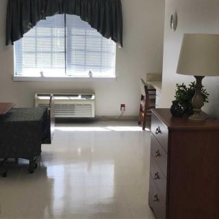A tidy room with a window, lamp, and cabinet.